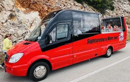 Robin in yellow jacket walking by the red and black sightseeing convertible van in Korcula, Croatia